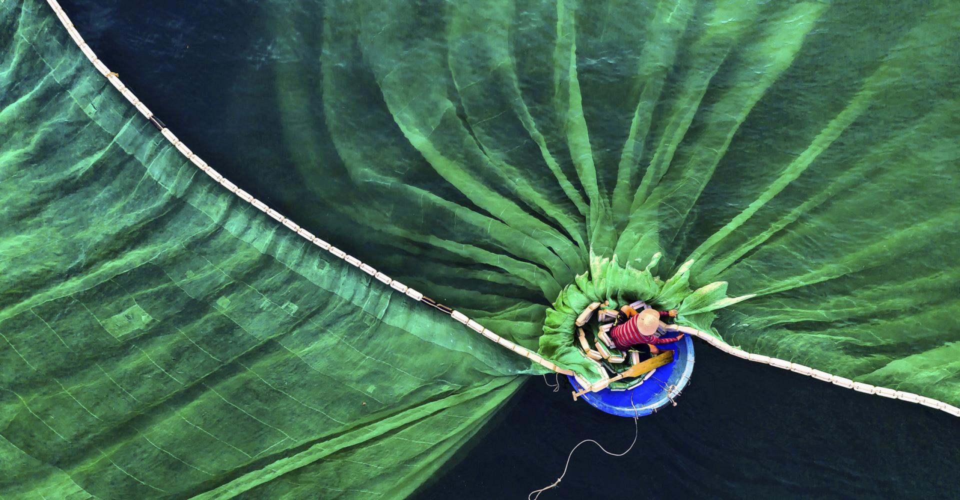 Aerial vie of fisherman in boat throwing nets on water